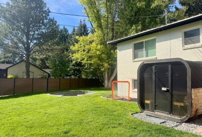 Fenced backyard lawn with the private barrel sauna