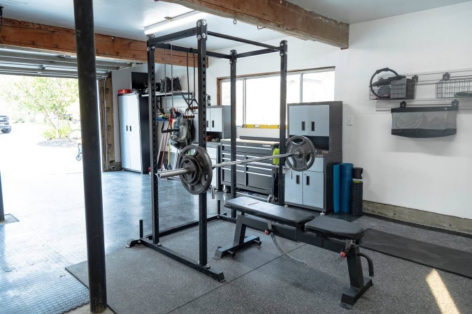 Two-car garage set up as a gym with a squat rack and bench